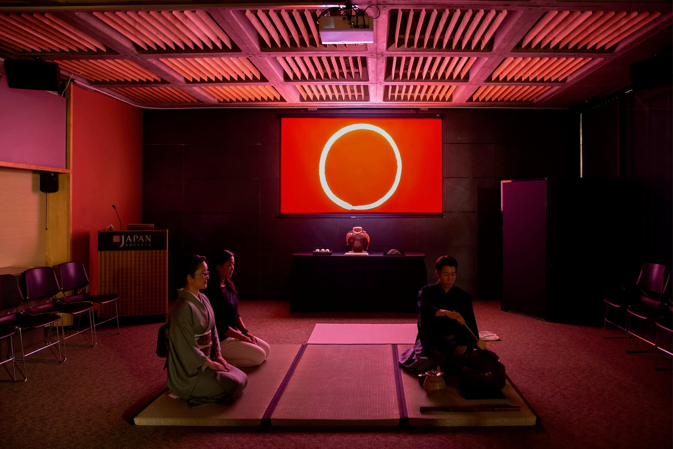 A tea ritual at Japan Society, performed before a projected red ensō
